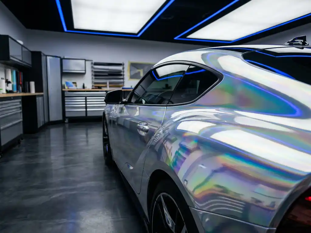 Sportwagen volledig bespoten met spiegelchroom vinylwrap, met regenboogreflecties in een professionele wrapstudio.