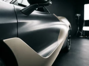 Sportwagen met satijnen vinylwrap in metallic grijs, zachte studioverlichting benadrukt de fluwelen textuur op het portier.