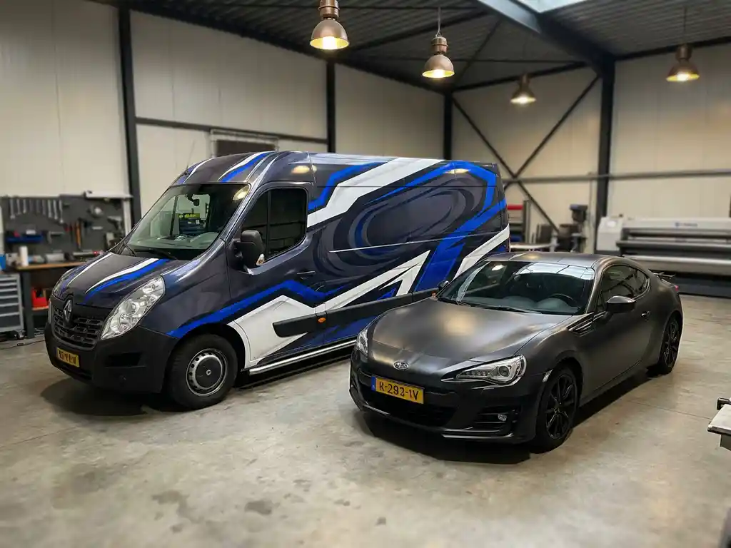 Beklede bezorgbus met levendige reclamefolie naast matte zwarte auto in modern Nederlands autobekledings atelier.